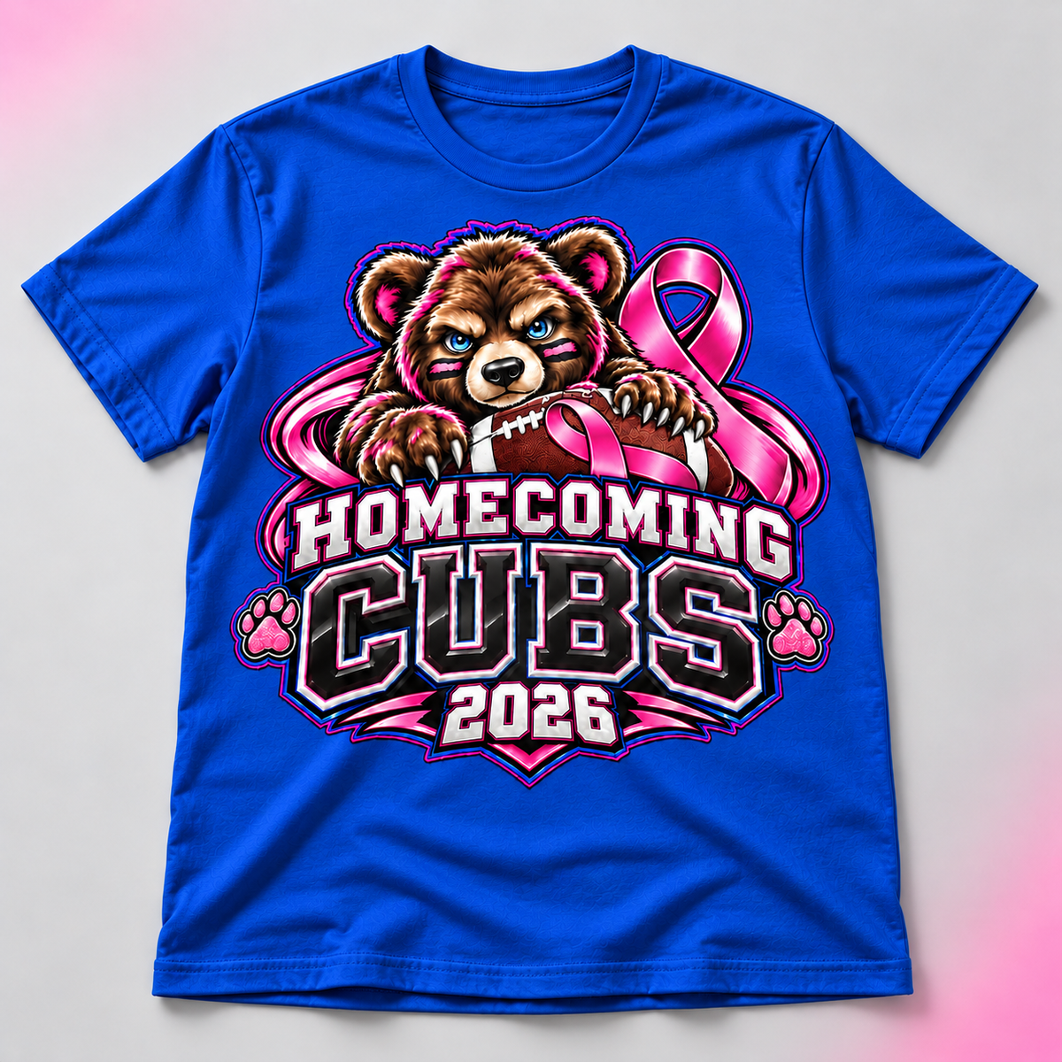 Royal blue Cubs Homecoming 2026 shirt with brown bear and pink awareness ribbons