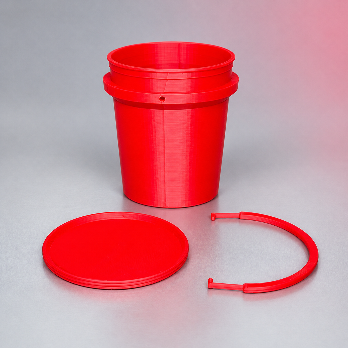 Red mini 3D-printed bucket with its separate round lid and curved handle on a silver-gray studio background.